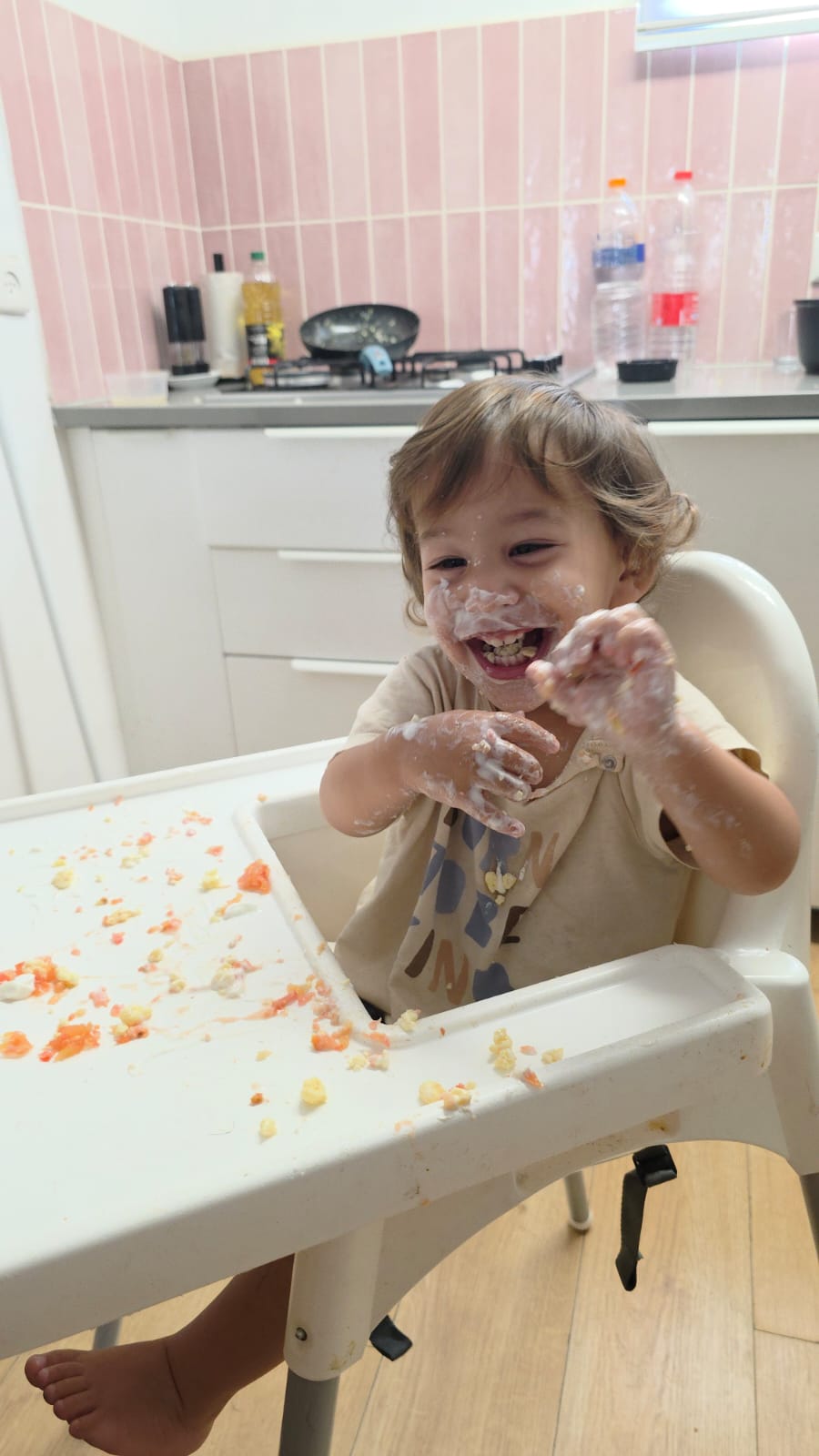 Bébé Eylor rit avec de la nourriture sur les mains et le visage.