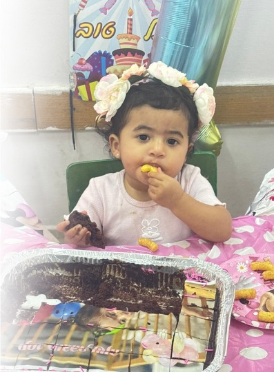 ElEliah, avec des fleurs dans les cheveux, mange un gâteau d'anniversaire à la garderie.