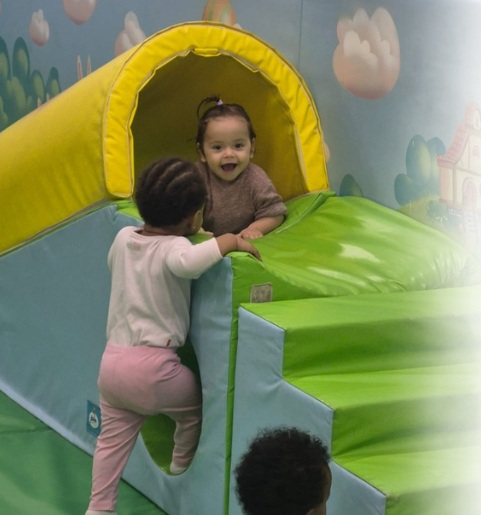 Ilay et un autre bébé jouent sur un toboggan jaune et vert