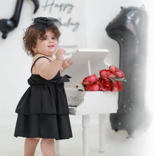 Séance photo de bébé Liah pour son premier anniversaire avec des fleurs sur un piano à queue