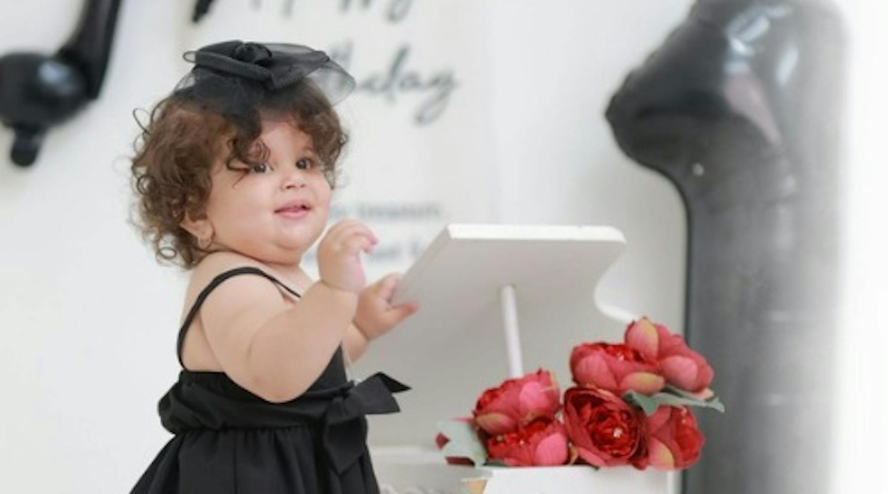 Séance photo de bébé Liah pour son premier anniversaire avec des fleurs sur un piano à queue