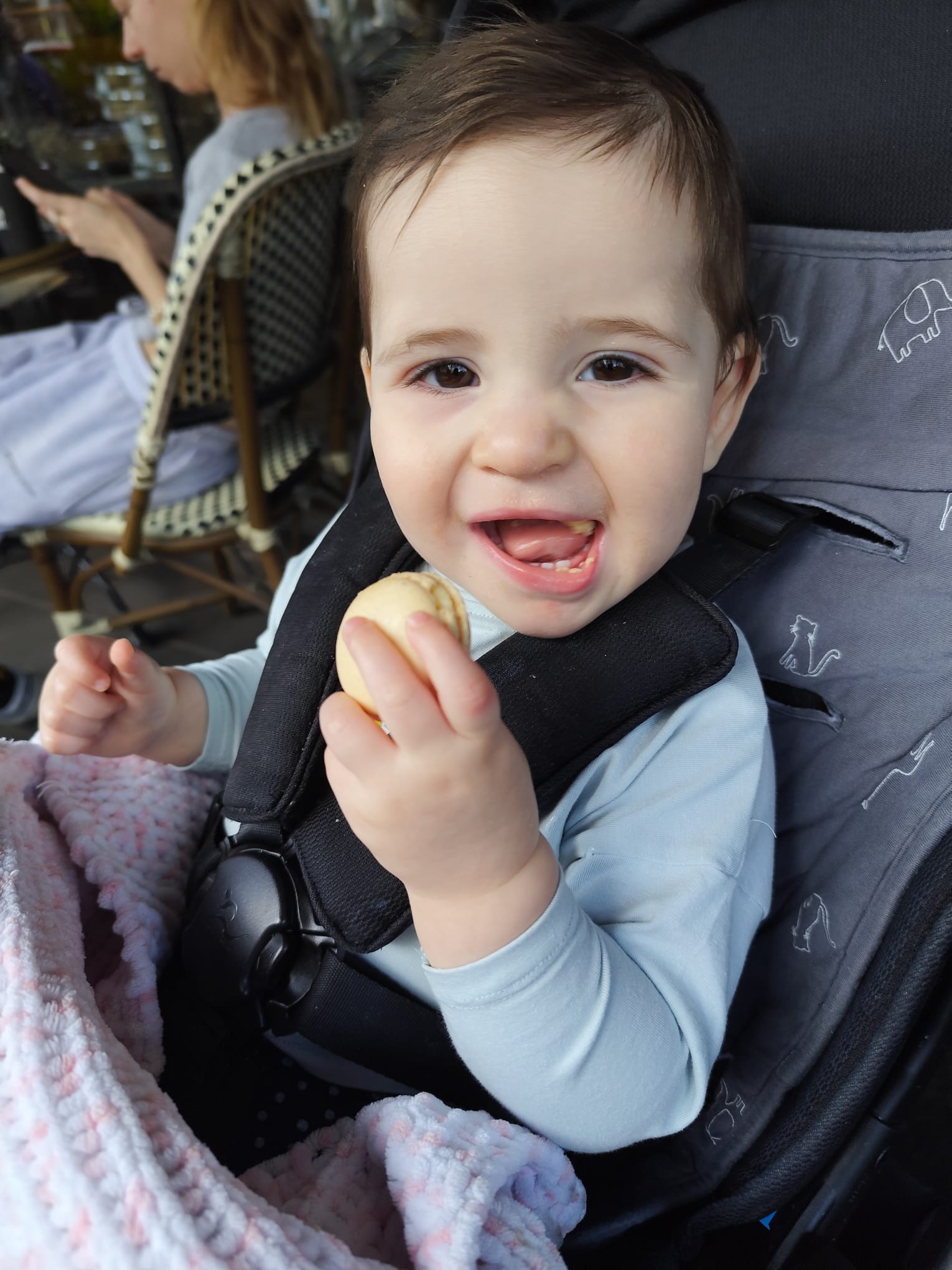 Lee sitting in a stroller with a huge smile and a cookie in her hand