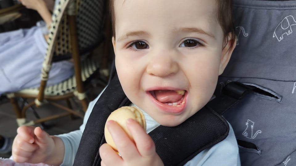 Lee sitting in a stroller with a huge smile and a cookie in her hand