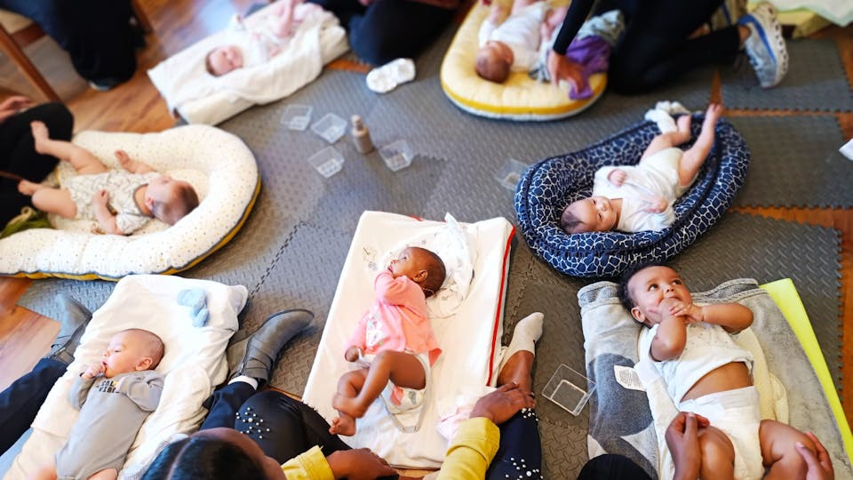 babies on blankets in a circle on the floor while their mothers gently massage them