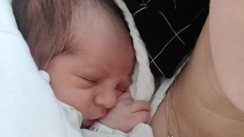 pasgeboren baby ligt op de schouder van zijn moeder