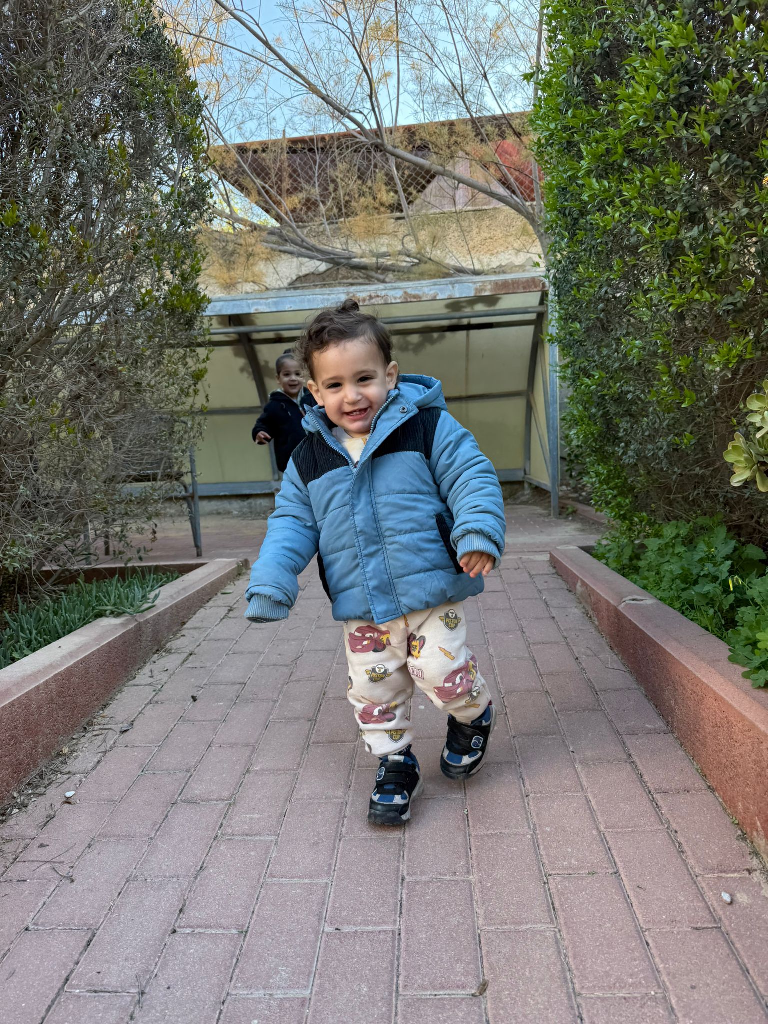 boy in blue jacket walking down a path