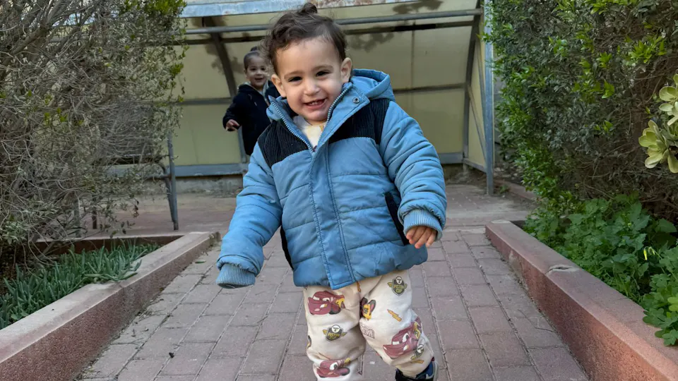 boy in blue jacket walking down a path