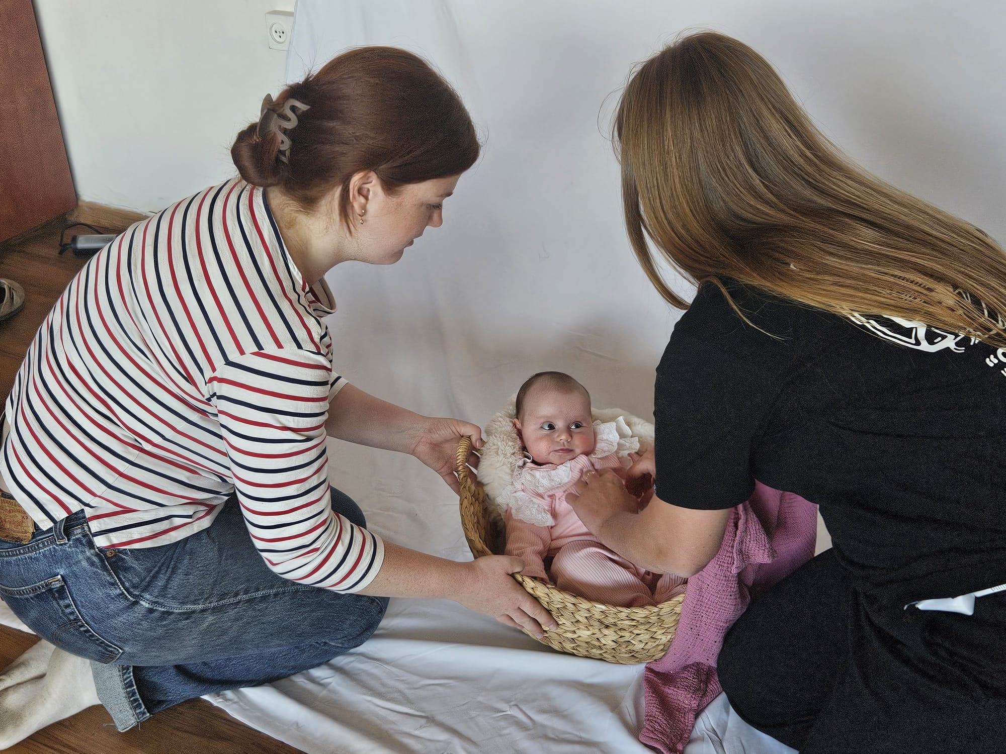 Onze fotograaf en een van de moeders maken het baby'tje klaar in een mandje voor de fotoshoot.
