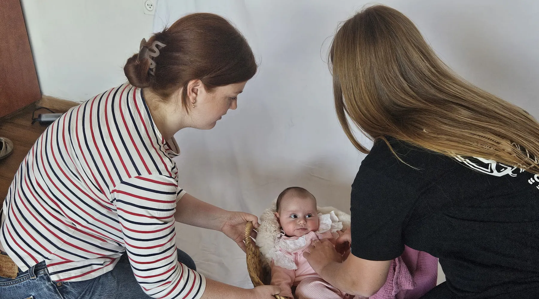 Onze fotograaf en een van de moeders maken het baby'tje klaar in een mandje voor de fotoshoot.