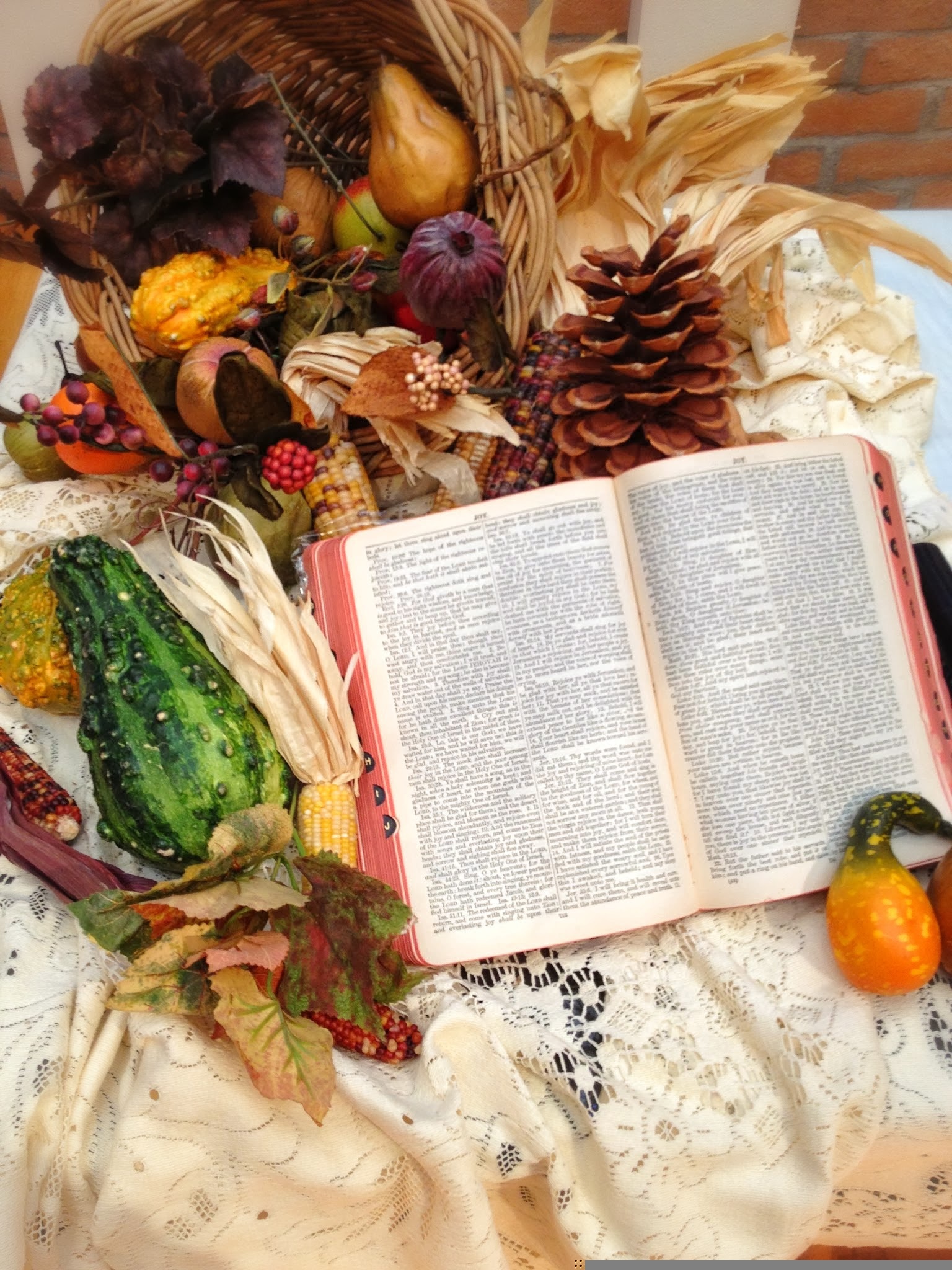 een opengeslagen bijbel op een tafel met pompoenen, kalebassen en andere herfstdecoraties