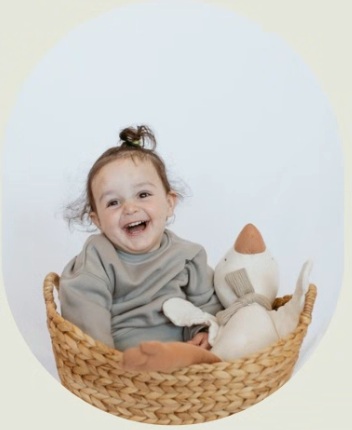 Roni with the biggest smile sitting in a basket next to a goose