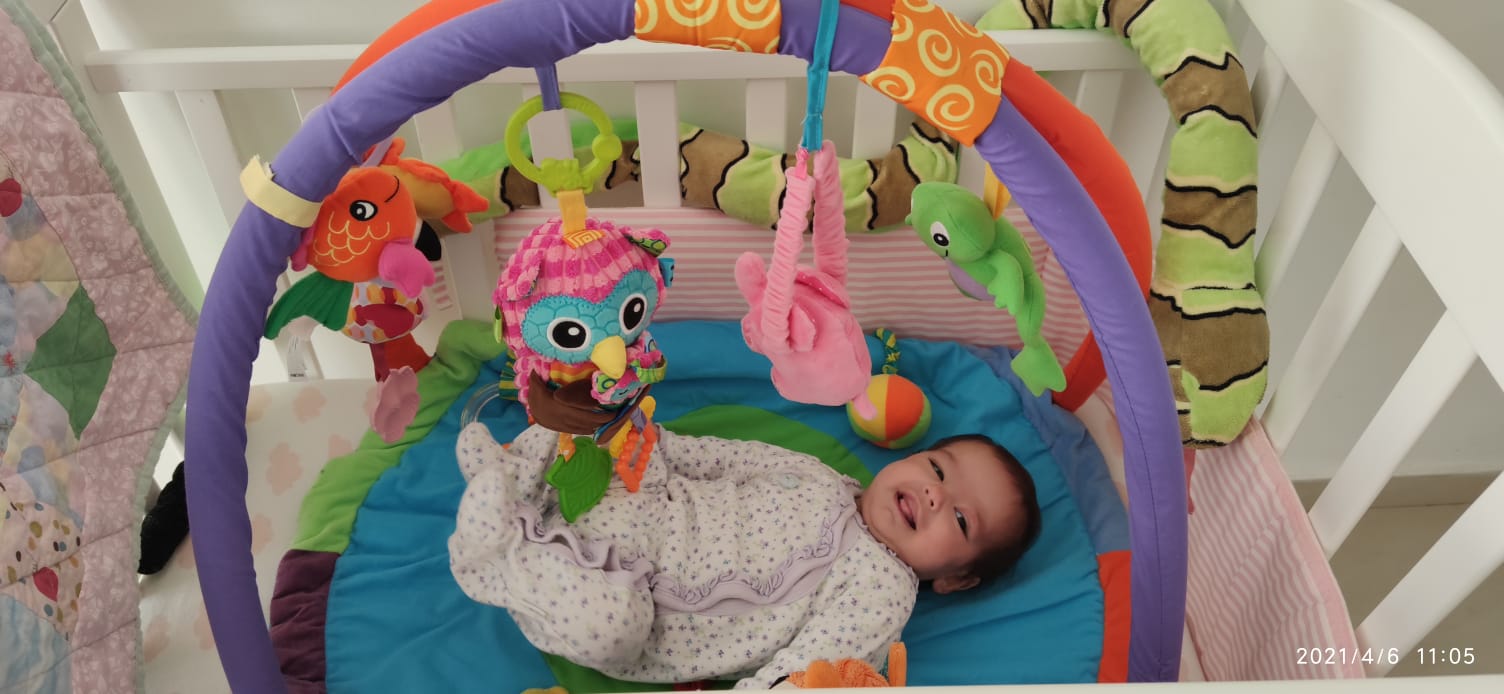 Halleli, geboren in 2021, lacht in haar babygym.