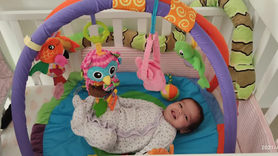 Halleli, geboren in 2021, lacht in haar babygym.