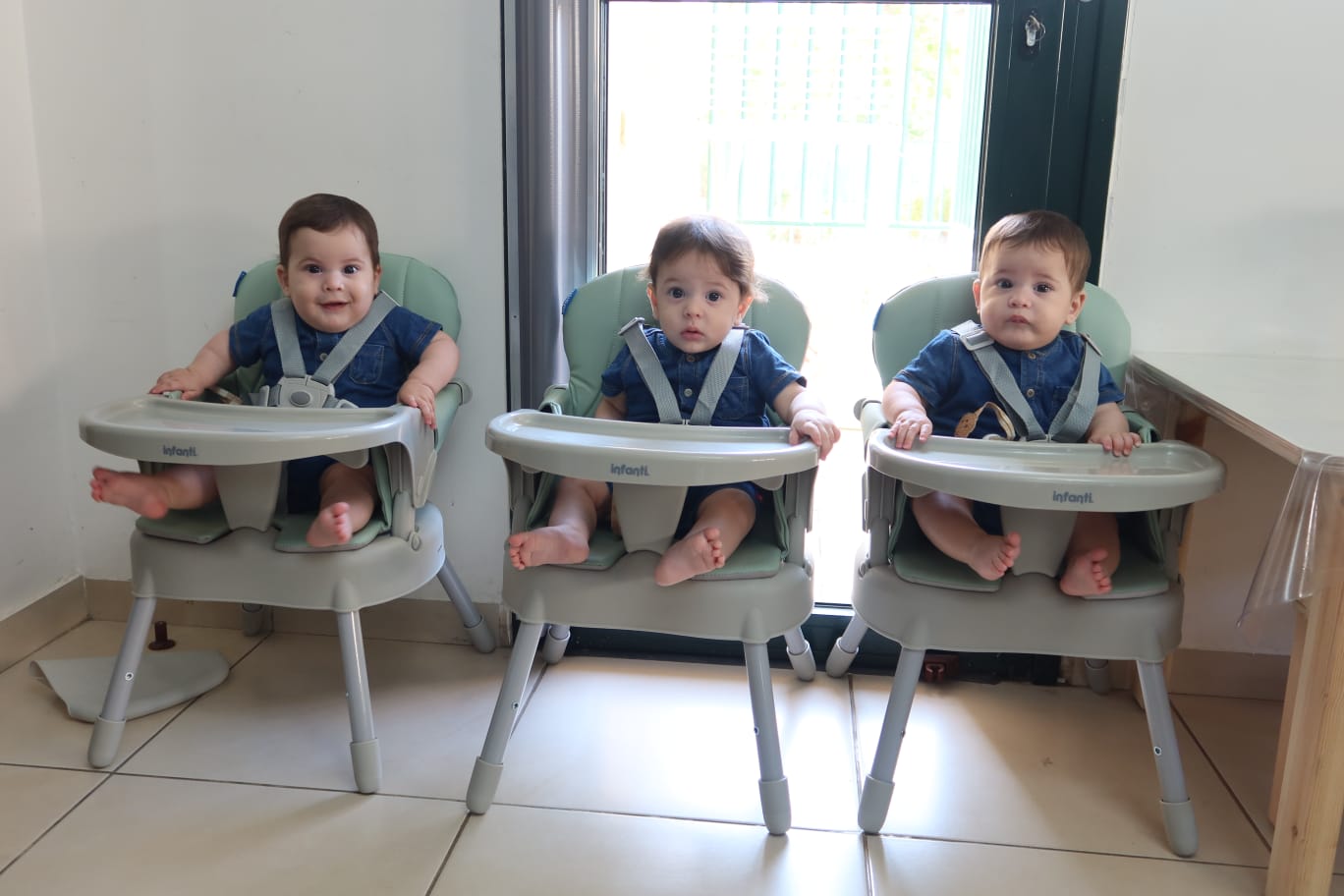 One year old boy triplets sitting in their high chairs