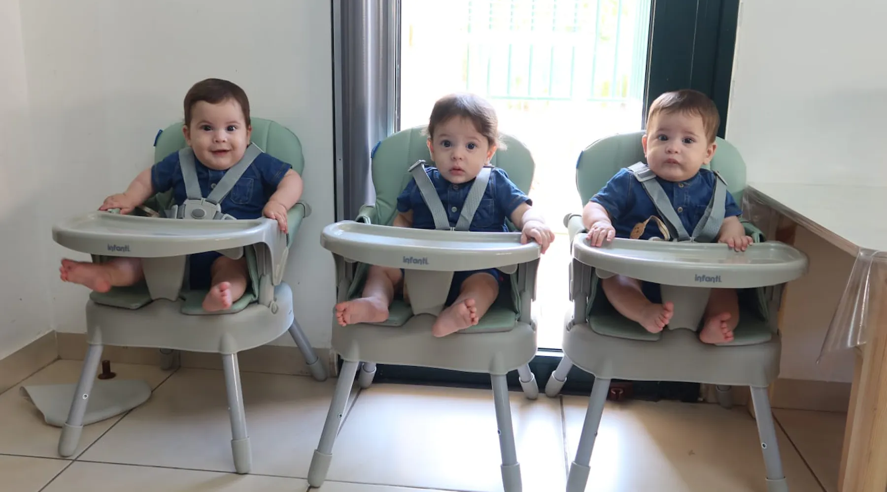 One year old boy triplets sitting in their high chairs
