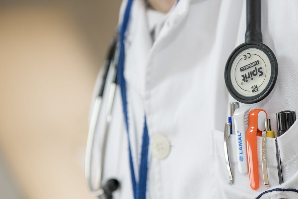 Closeup of a doctor's coat, showing pens and a stethoscope.