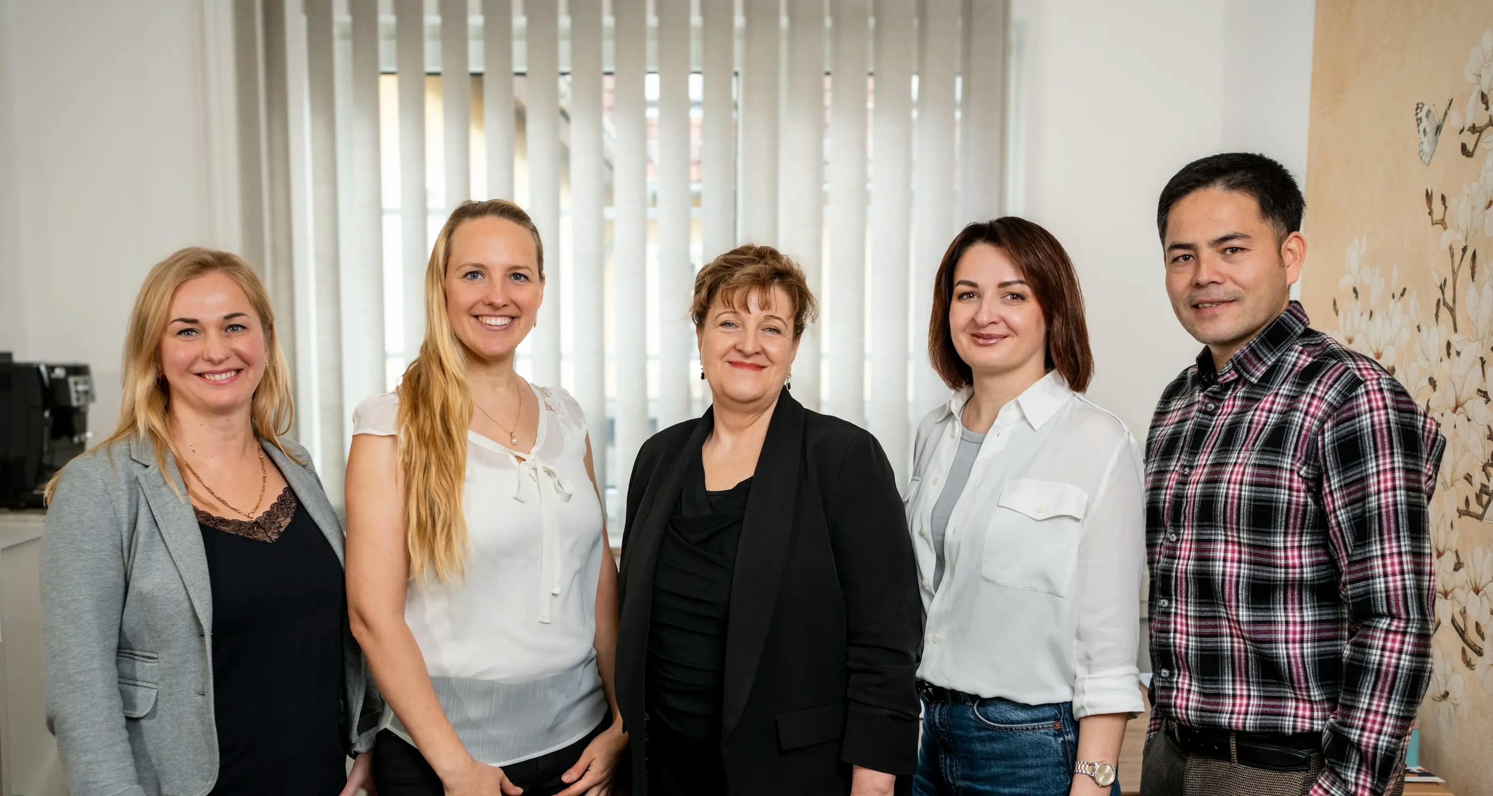 Gruppenfoto vom Team im Büro. Vier Frauen und ein Mann stehen nebeneinander.