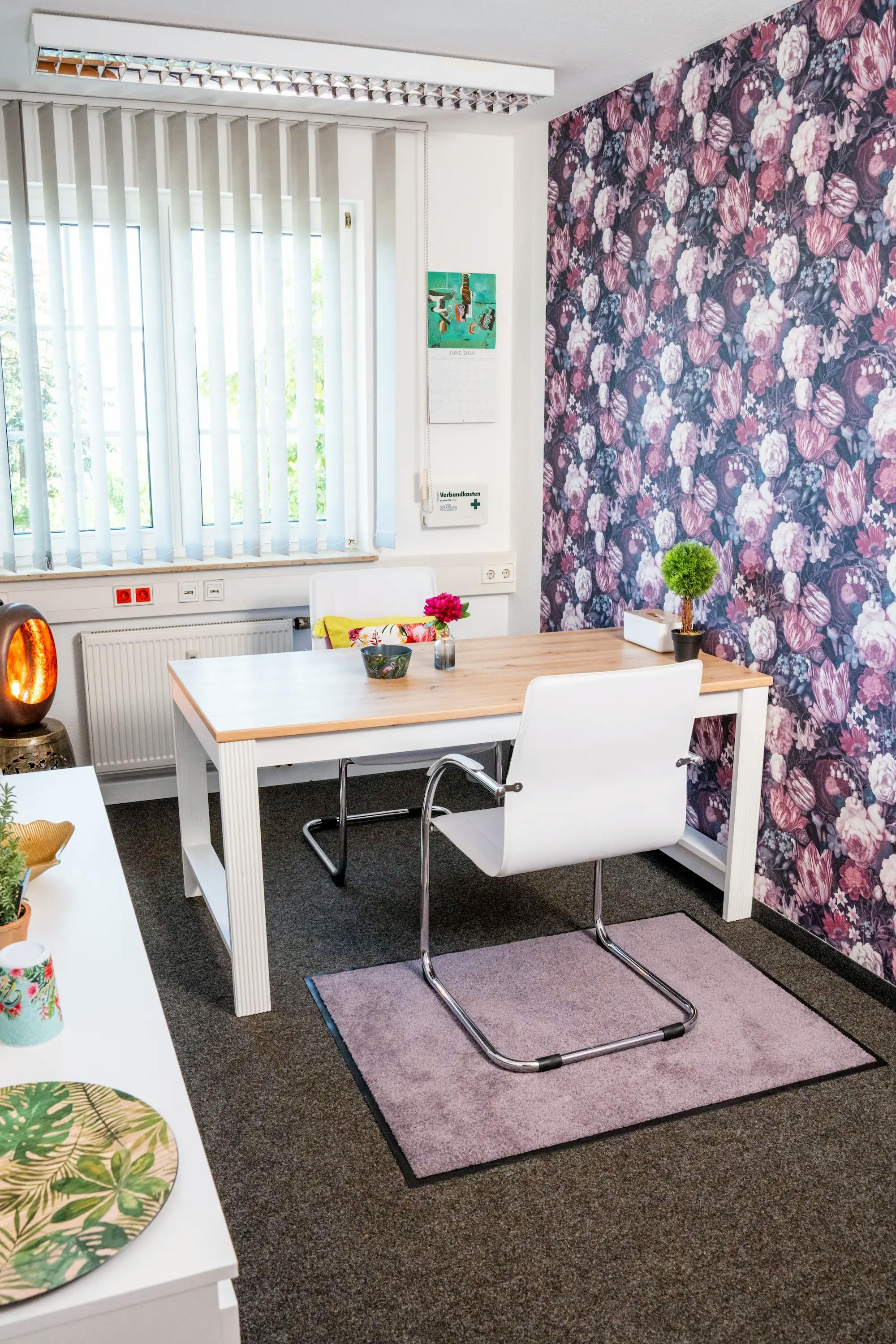 Helles Büro mit Tisch, zwei Stühlen und violetter, gemusterter Tapete