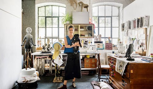 Cathie Pilkington in her studio, with Tulip. earing made to measure cotton drill 3/4 length trousers and a cotton-lycra top.