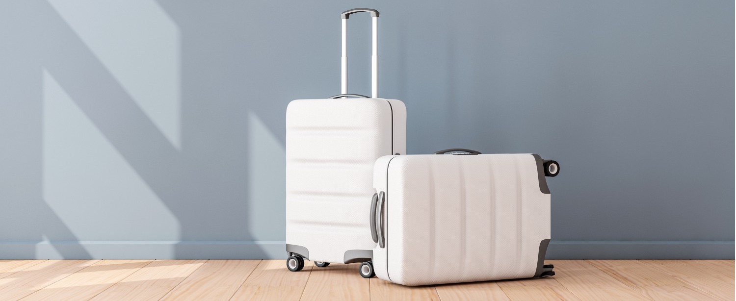 An image of two white suitcases against a grey-blue wall in a home. Examine the pros and cons of short-term and long-term rental for your home or real estate investment.