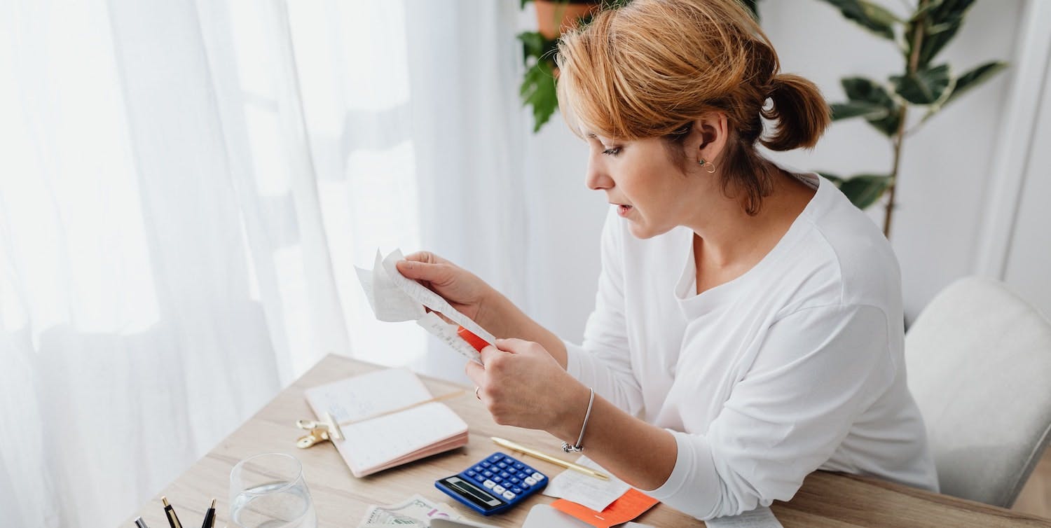 A woman examines receipts and rental cash flow, learning how to manage accounting as a first-time landlord