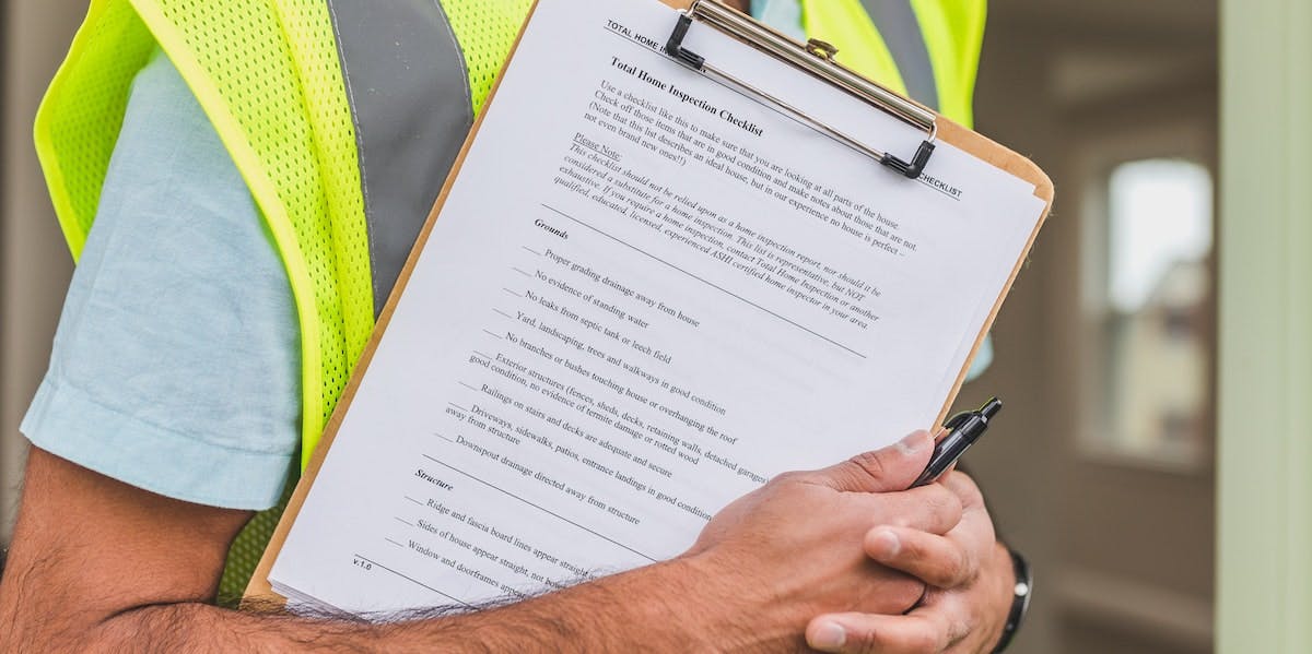 A man carries a clipboard to conduct a home inspection for a rental property