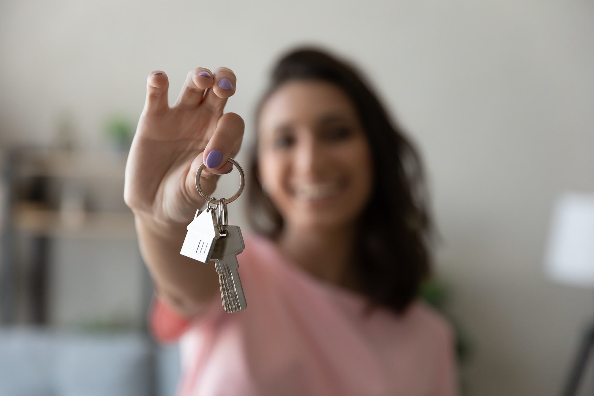 Woman holding keys to rental property and smiling, taking a human approach to renting out property