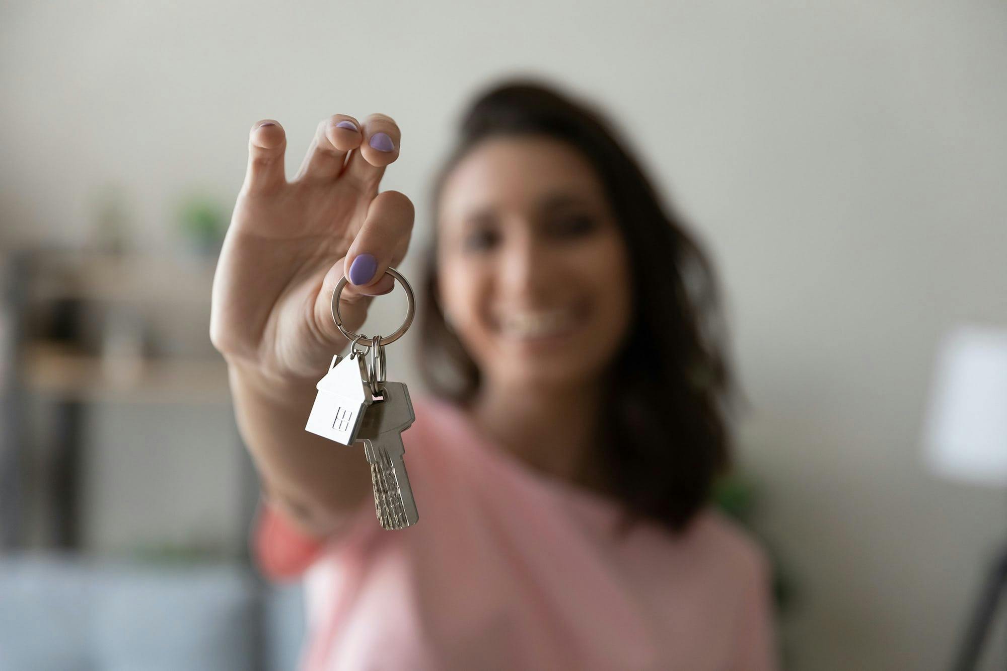 Woman holding keys to rental property and smiling, taking a human approach to renting out property