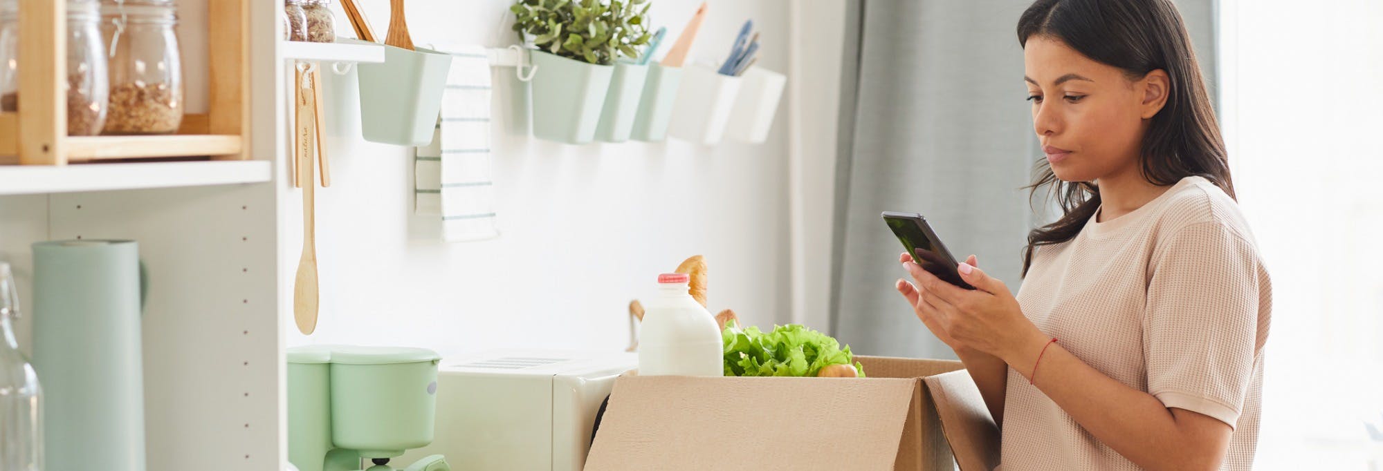 Woman using a mobile phone to order home delivery of groceries 