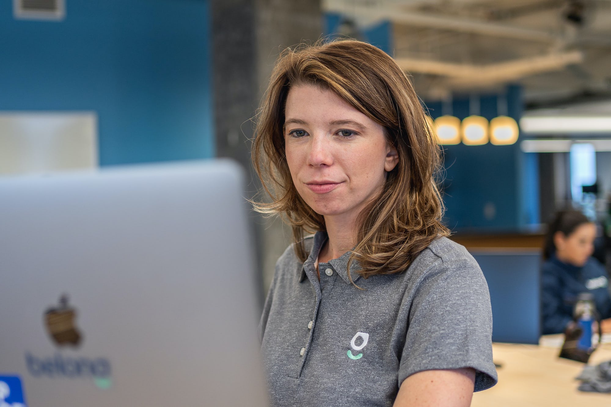 A Belong employee working in the Belong headquaters office, on a Mac computer 