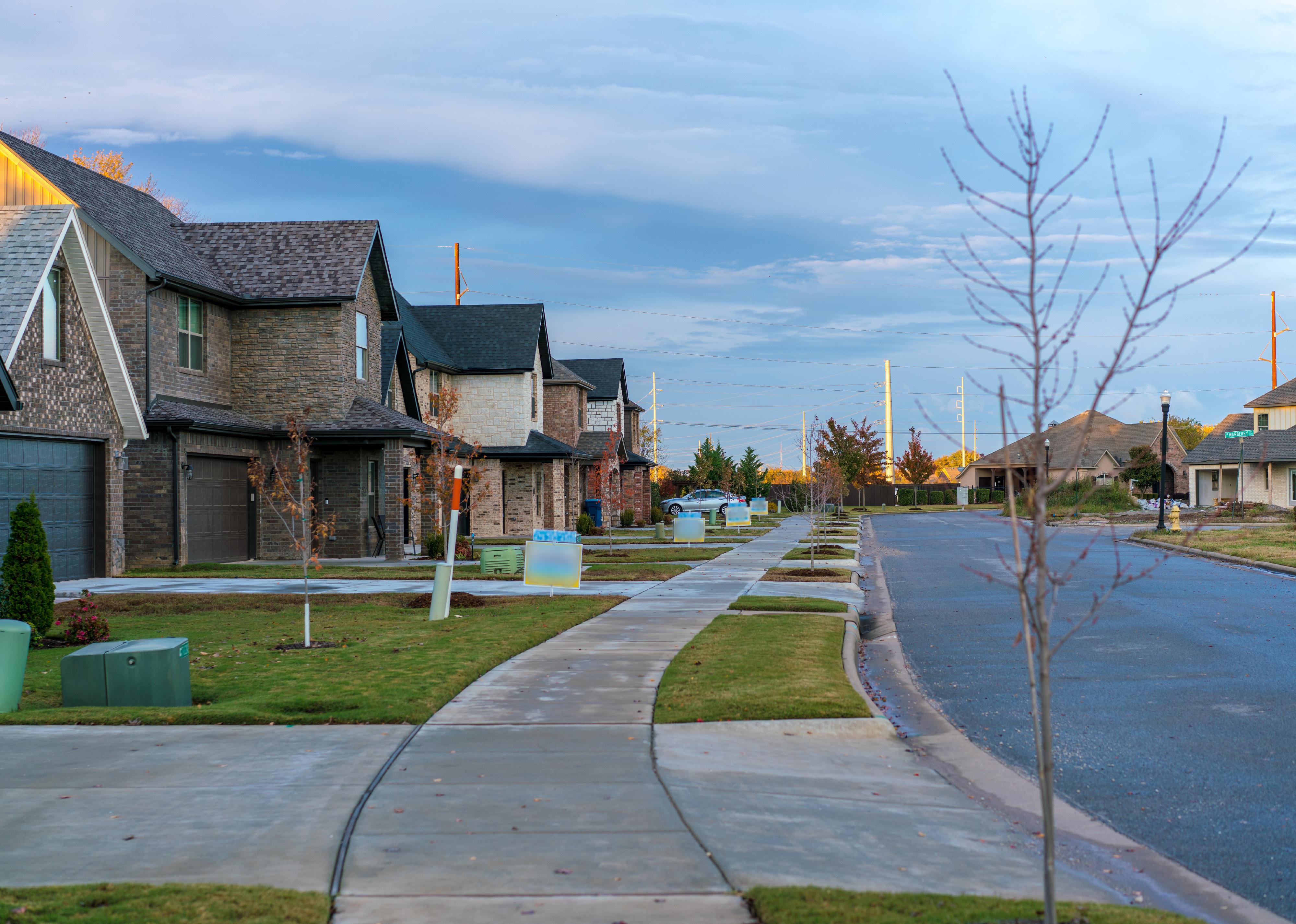 A quite suburban street with rain clouds and wet sidewalk and road