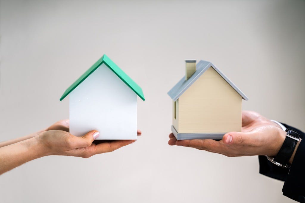Hands holding two similar like-for-like homes, depicting what landlords should know about 1031 exchange rules