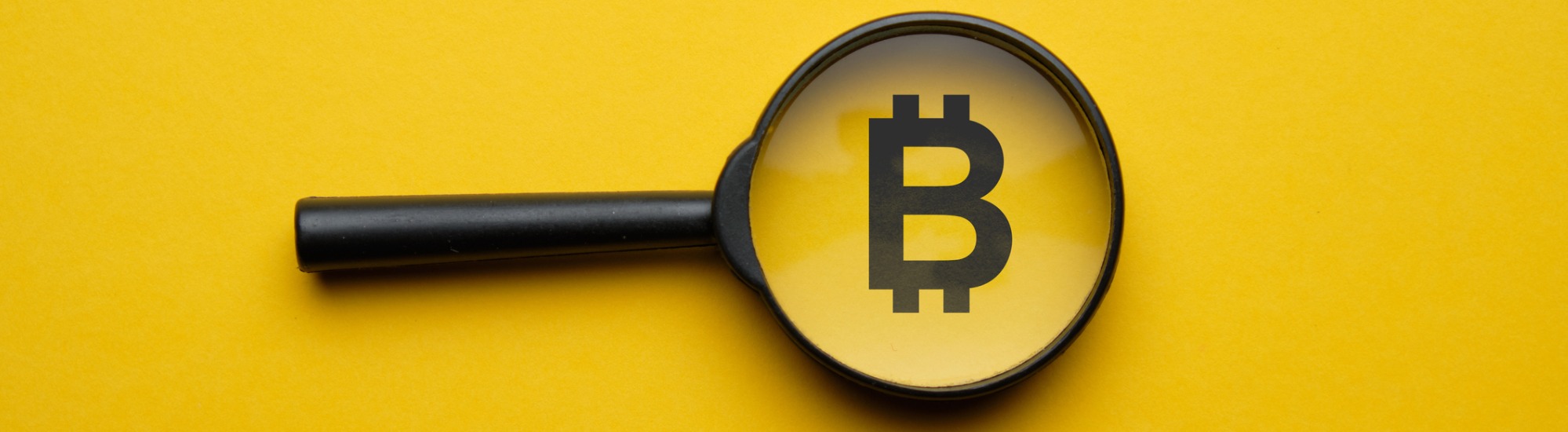 A magnifying glass over the Bitcoin symbol