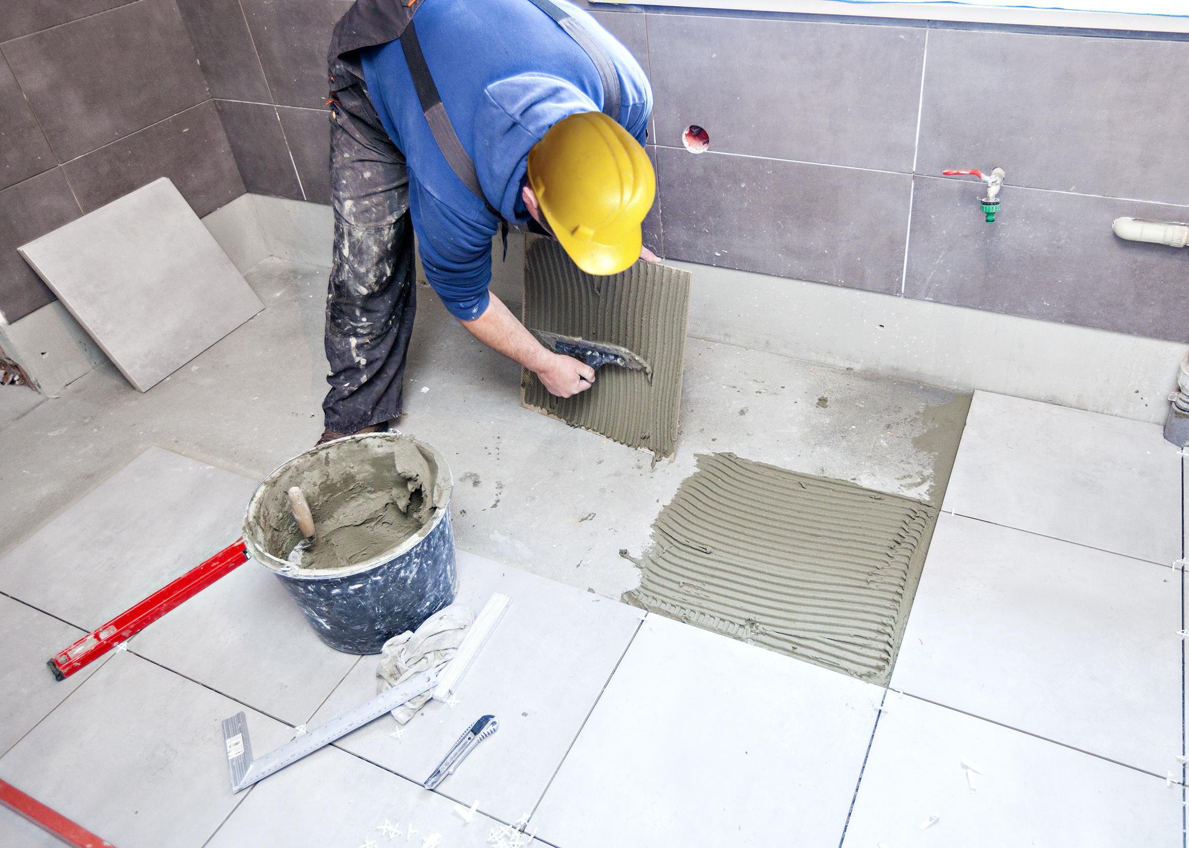 A tiler is replacing grout and bathroom tiles