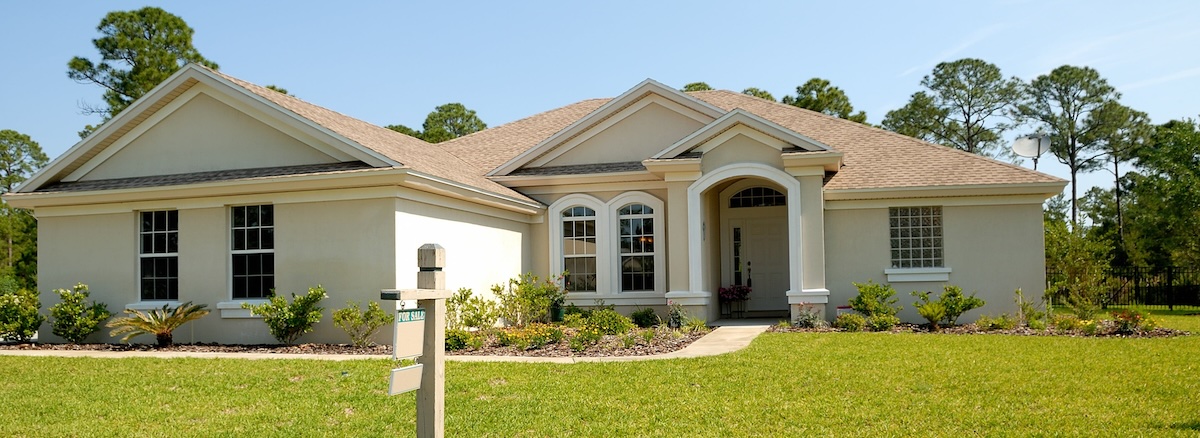 A detached white and beige single family home with well kept lawn