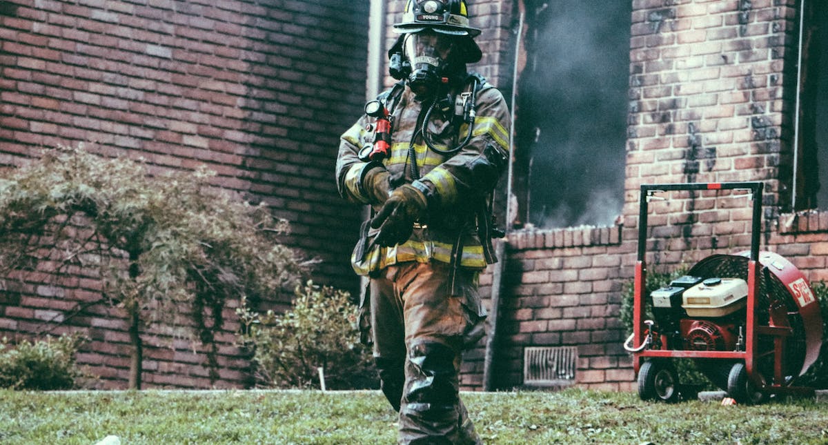 A photo of a firefighter at a house fire. Fire damage is a common threat for landlords and their rental homes.