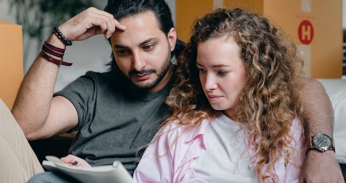 A young couple are looking over paperwork with moving boxes in the background. Sometimes residents need to terminate their rental lease agreement early, find out how to manage a break-lease for your rental home.