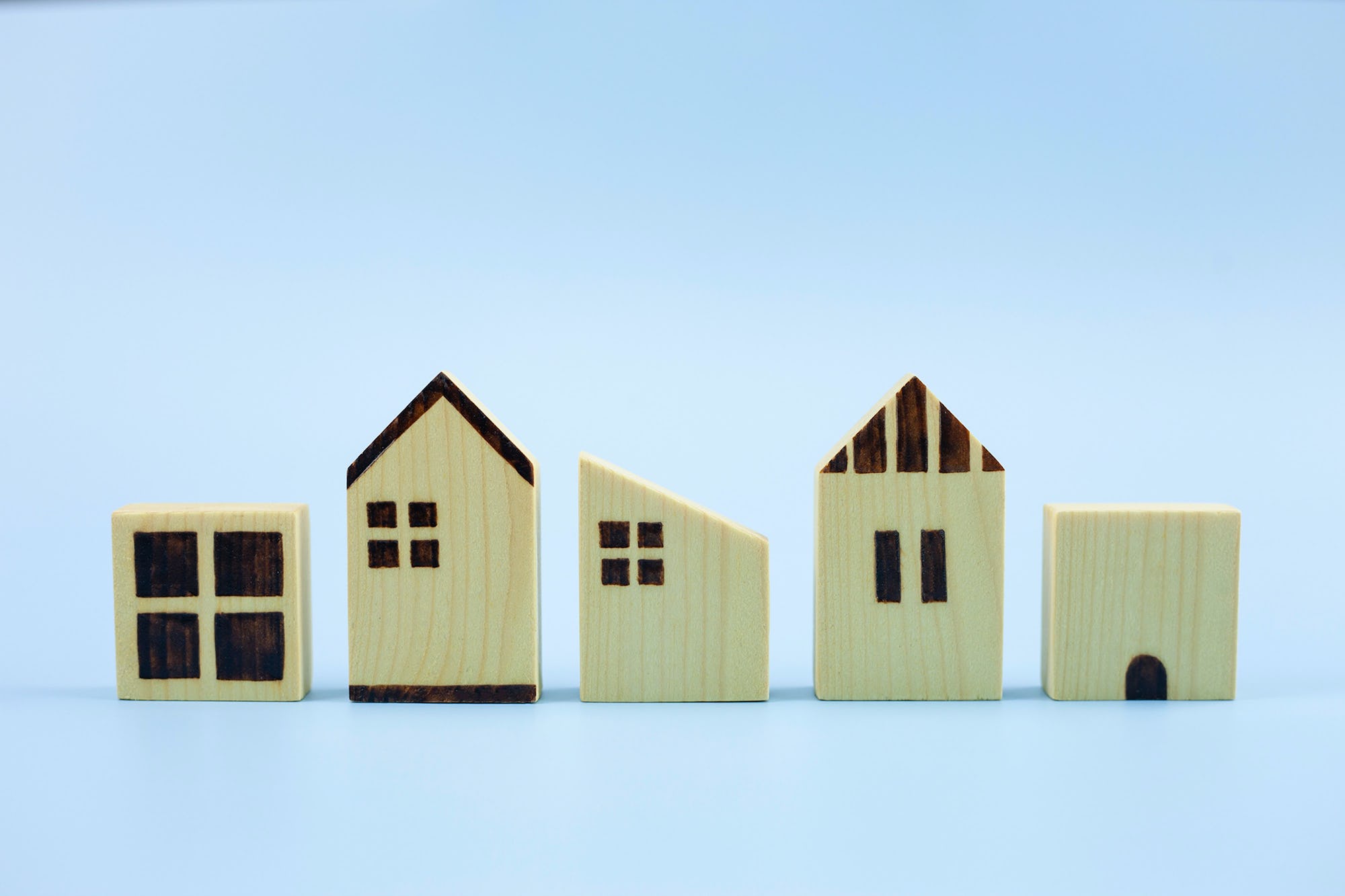 Display of small wooden houses in a row of all different shapes and sizes, reflecting diverse community of homeowners and renters