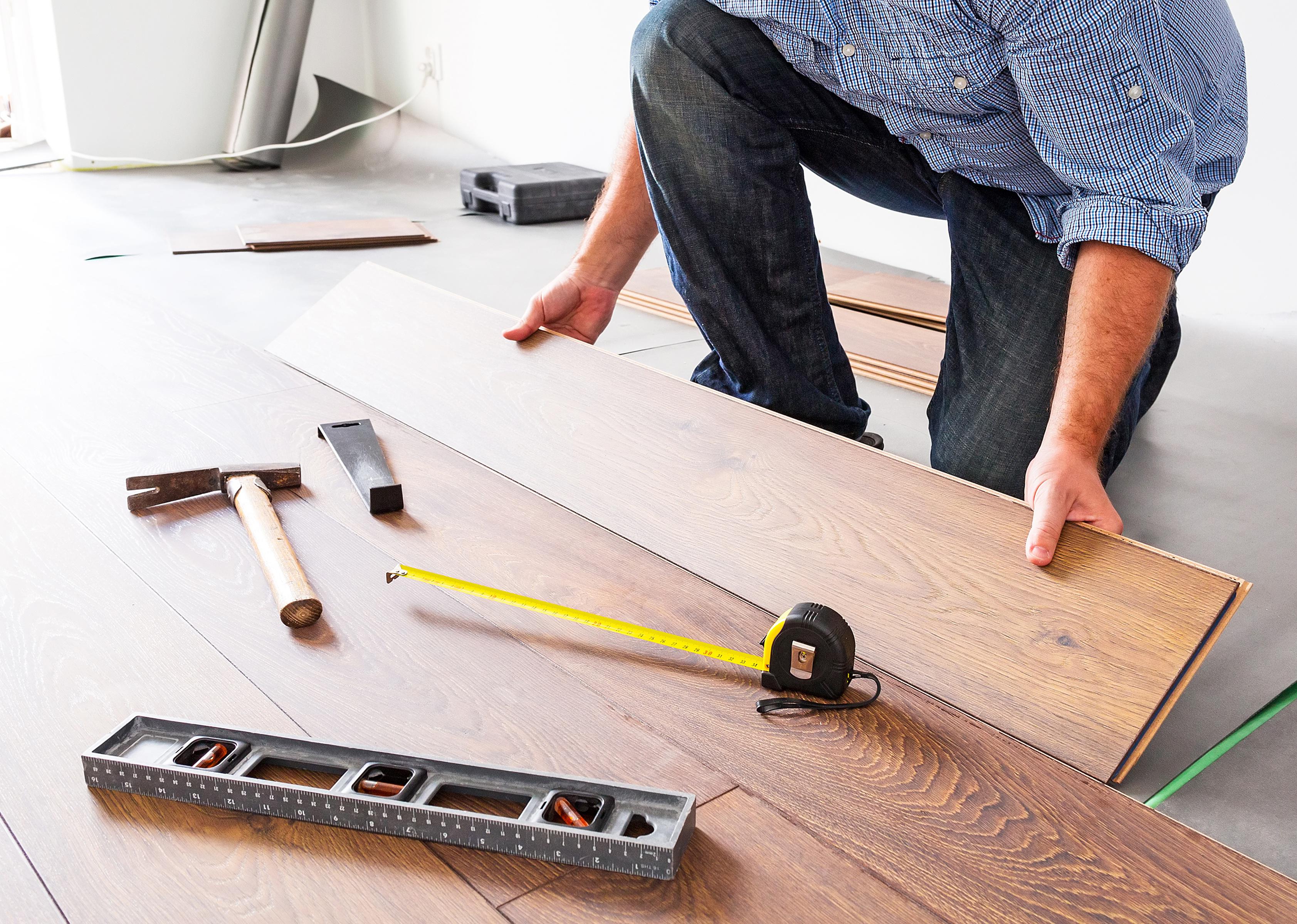 New wooden flooring is being laid in a home, with a measuring tape and tools visible