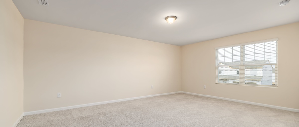 The empty room of a vacant rental home, with off-white walls and a window