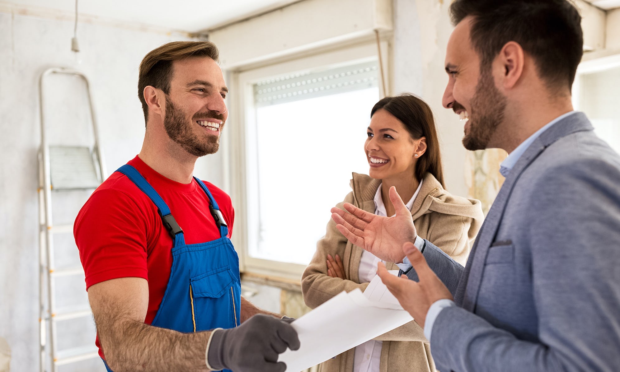Homeowners discussing repairs and home renovation with a friendly tradesperson, contractor