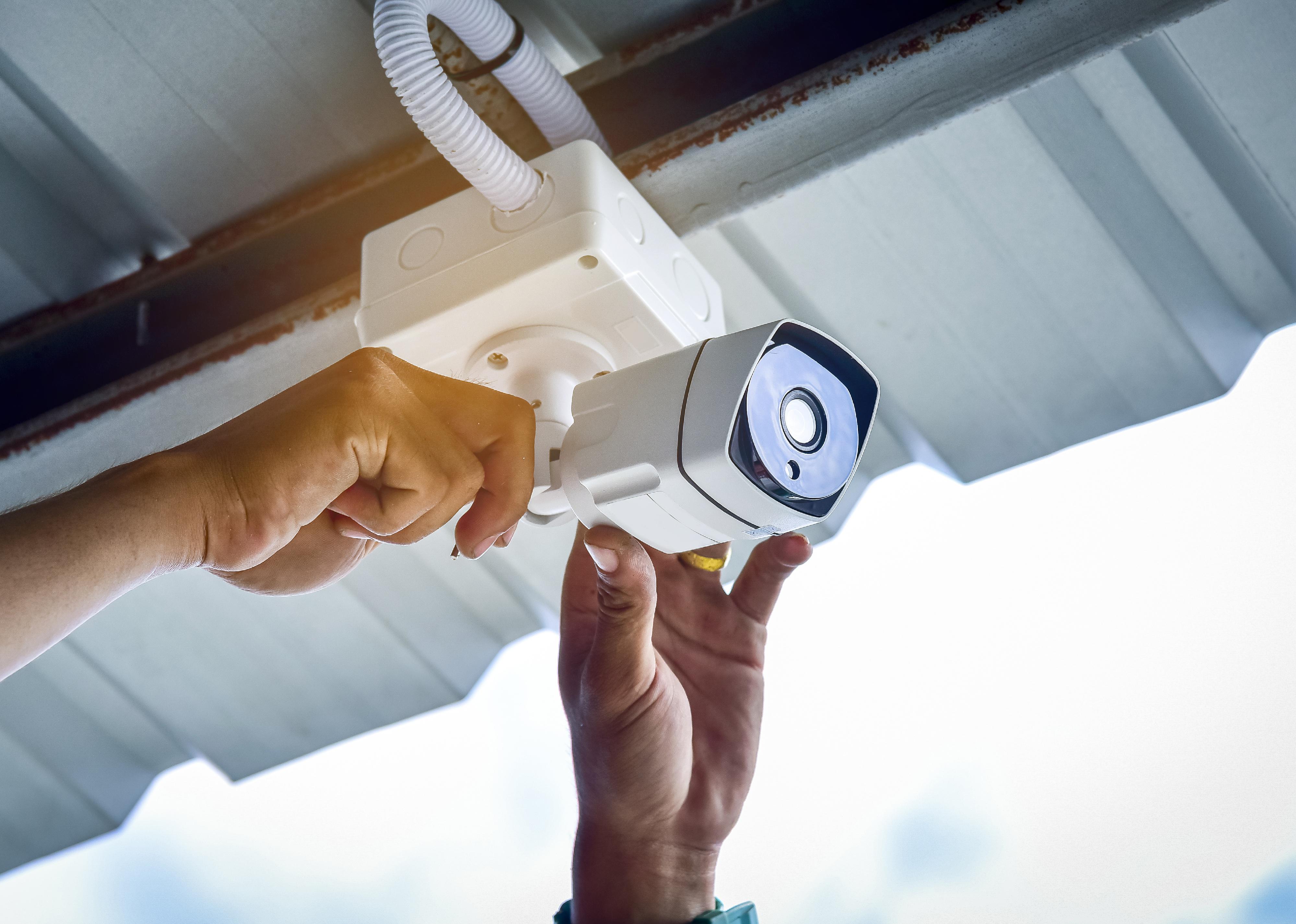 A hand installs a security camera to a rental home