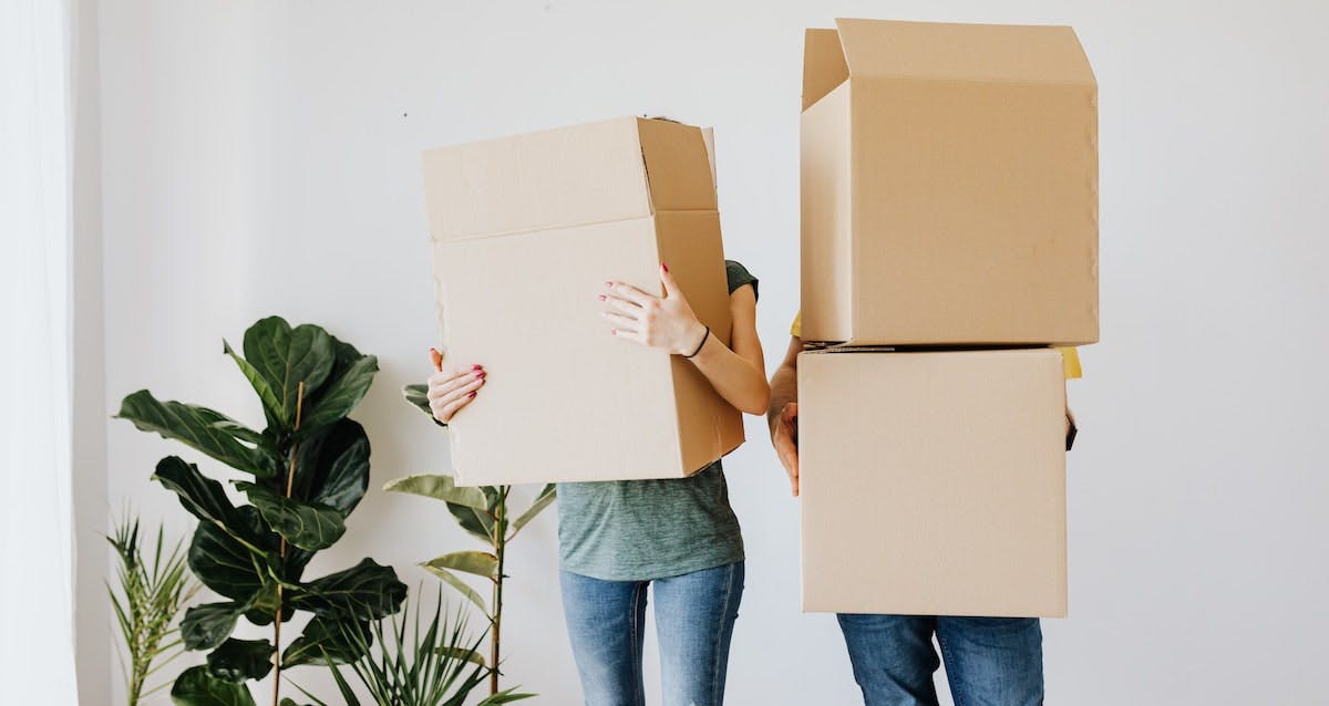 A couple with moving boxes and house plants, new residents of a rental home. Find out how to attract the great tenants to your rental property. 