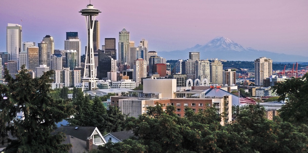 An image of the Seattle city skyline, with a view of houses and condos in the foreground. Learn more about where to invest in Seattle real estate. 