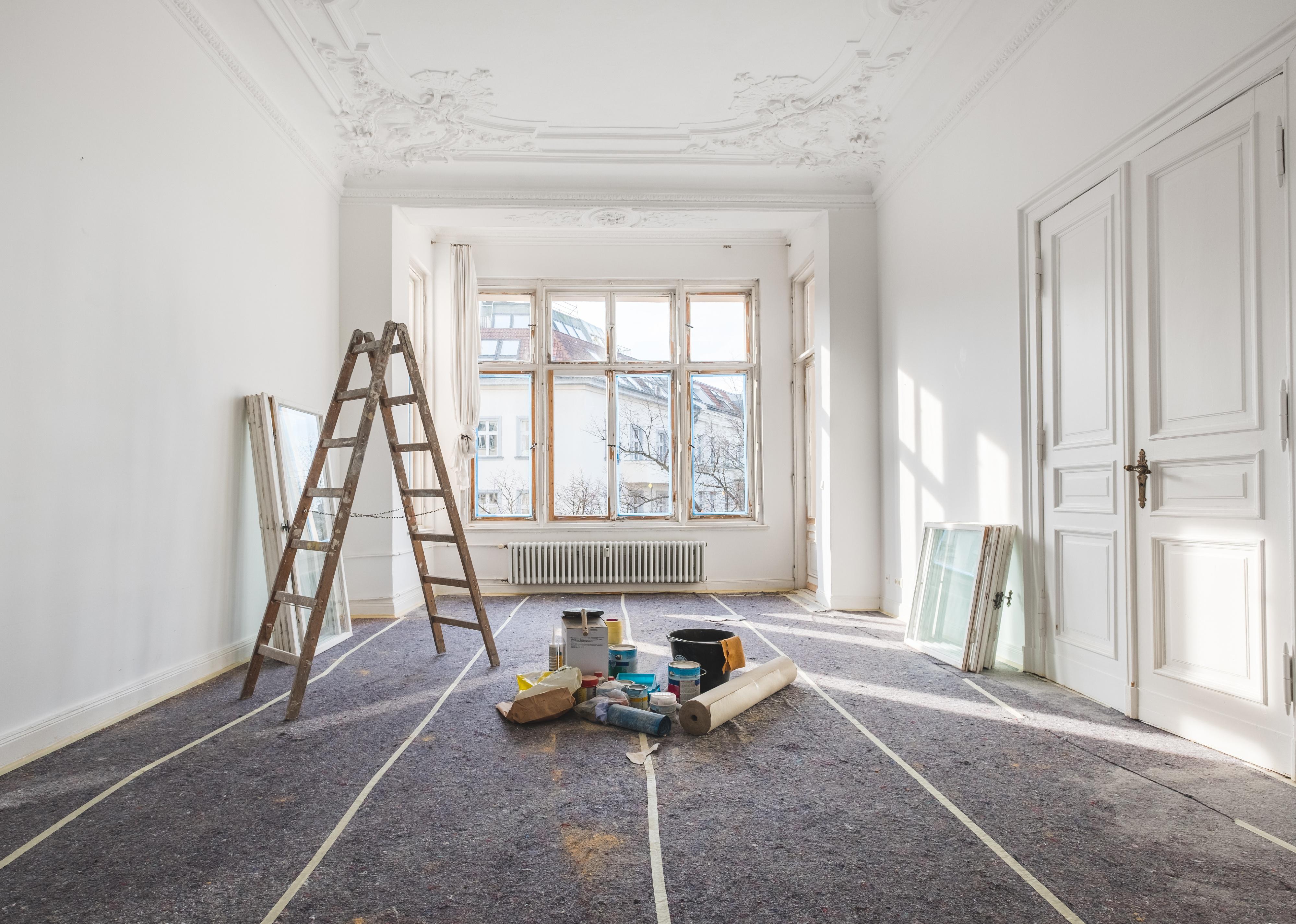 A vacant home filled with a ladder and paint supplies for renovation