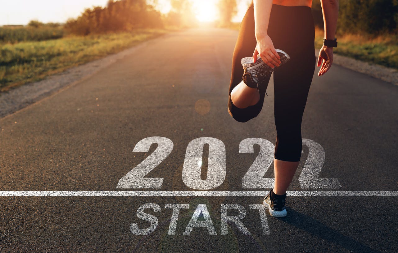 Woman stretching and preparing to run a race, with the year 2022 depicted as the starting line