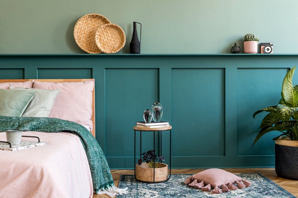 An on-trend bedroom with two shades of green paint, moulding and soft furnishings