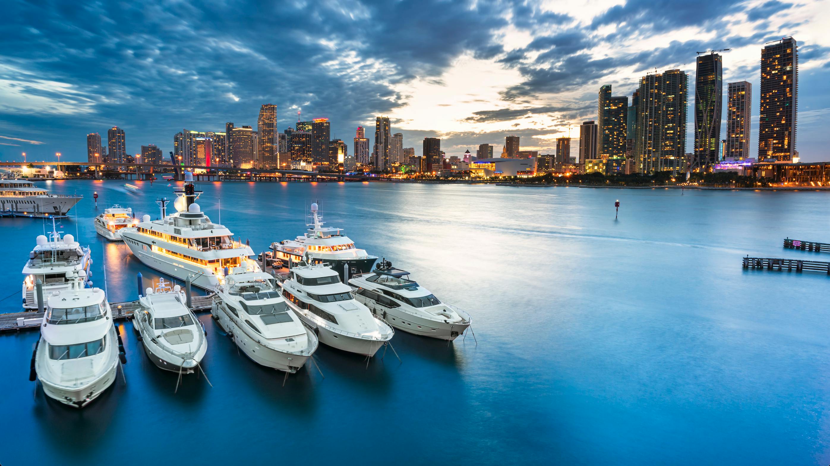 An image of a Florida harbor with boats lined up in the foreground and the Miami skyline in the background