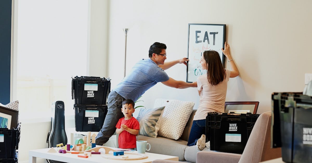 A family move into a new rental home, hanging artwork and unpacking boxes