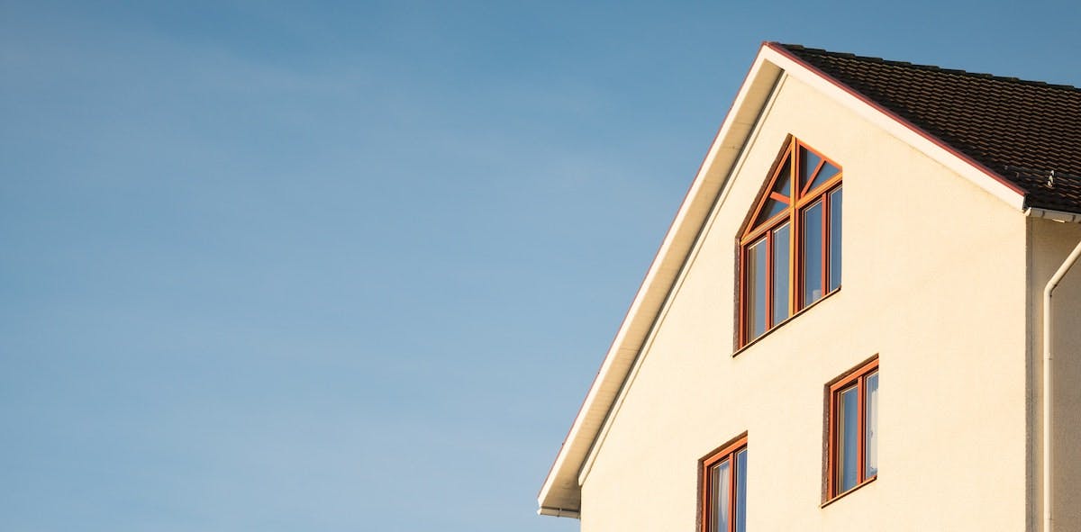 A partial image of a house with windows against a blue sky. Learn how to create a lease for your real estate investment. 